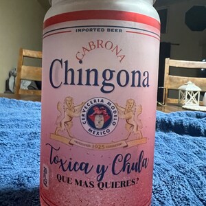 K&ouml;nnte beinhalten: Eine rosa und wei&szlig;e Dose mit einem roten Streifen und einem Holzdeckel. Die Dose hat ein Logo mit einem L&ouml;wen und dem Text "Cerveceria Modelo Mexico 1925". Der Text "Cabrona Chingona Toxica y Chula Que Mas Quieres?" ist auf der Dose aufgedruckt. Die Dose wird in Mexiko hergestellt.