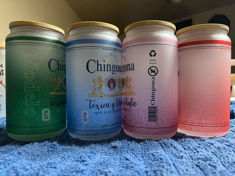K&ouml;nnte beinhalten: Vier gefrostete Glas-Bierdosenbecher mit Bambusdeckeln. Die Becher sind gr&uuml;n, blau, rosa und rot. Der gr&uuml;ne Becher hat den Text "Modelo" darauf. Die blauen und rosa Becher haben den Text "Chingona" darauf. Der blaue Becher hat den Text "Toxica y Chula" darauf. Der rosa Becher hat den Text "please recycle" darauf. Der rote Becher ist leer.
