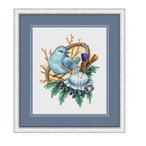 May include: A cross-stitch embroidery design featuring a blue bird perched on a branch with a needlepoint cushion, embroidery hoop, and needles. The design is surrounded by green leaves and purple berries.