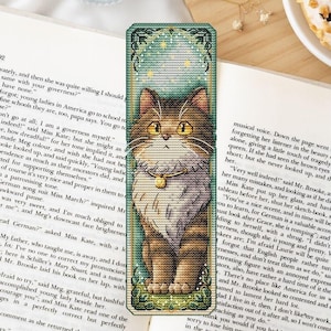 Op de afbeelding: Geborduurd bladwijzer met een gedetailleerd tabby kat ontwerp en een gouden halsband, tegen een turquoise en goudkleurige achtergrond. De bladwijzer is rechthoekig met een decoratieve rand en een groene basis.