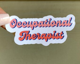 Pode incluir: Um adesivo branco com o texto "Occupational Therapist" em letras rosa e azul. O texto está em um estilo de fonte retrô.