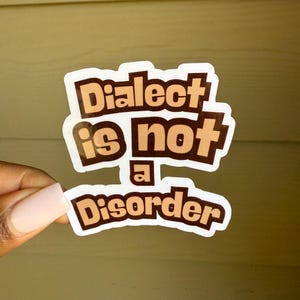 May include: A white sticker with brown text that reads "Dialect is not a disorder".