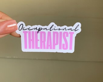 Puede incluir: Pegatina blanca con el texto "Occupational THERAPIST" en letra cursiva negra y letras rosas.