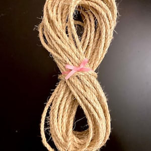 May include: A roll of natural twine tied with a pink ribbon. The twine is made of natural fibers and is perfect for crafting, wrapping, and decorating.