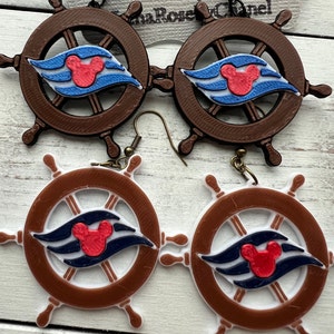 Könnte beinhalten: Ein Paar braune und weiße Schiffssteuerrad-Ohrringe mit einem blauen und roten Mickey-Mouse-Logo. Die Ohrringe sind aus Kunststoff und haben einen Hakenverschluss.