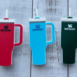 On the left is a red stanley with black logo, middle is blue stanley with darker blue logo and on theright is green stanley with white logo.