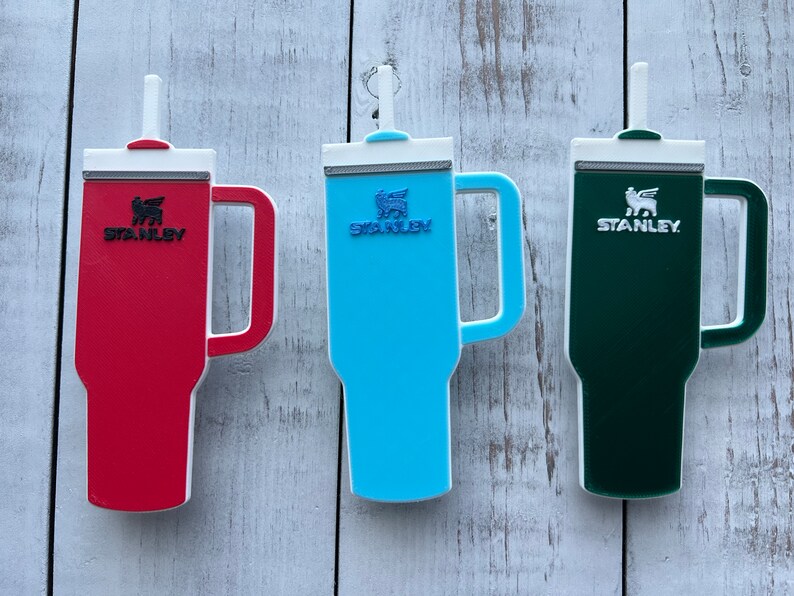 On the left is a red stanley with black logo, middle is blue stanley with darker blue logo and on theright is green stanley with white logo.