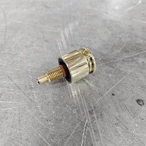 May include: A gold-colored metal valve with a threaded stem and a ball-shaped tip. The valve has a black rubber seal and a ribbed design.