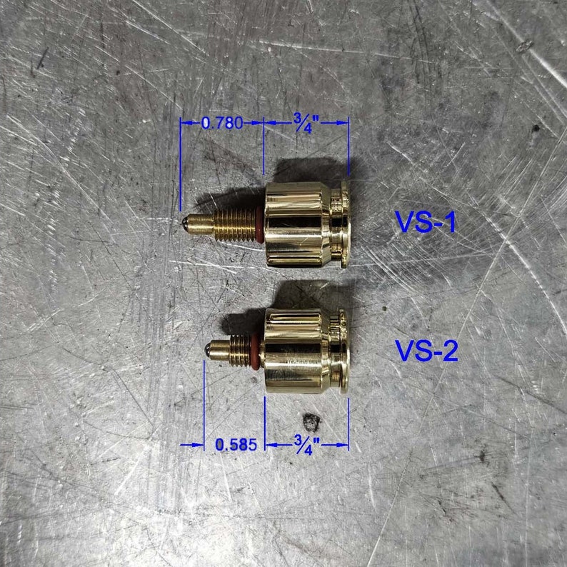May include: Two gold-colored metal fittings with red o-rings. The top fitting measures 0.780 inches by 3/4 inches and is labeled "VS-1". The bottom fitting measures 0.585 inches by 3/4 inches and is labeled "VS-2".