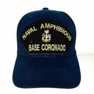 May include: A navy blue baseball cap with a black patch that reads "NAVAL AMPHIBIOUS BASE CORONADO" in gold lettering. The patch features a gold anchor.