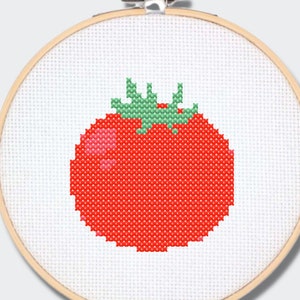 May include: A cross-stitch pattern of a red tomato with green leaves in a wooden embroidery hoop. The pattern is available as a PDF download.
