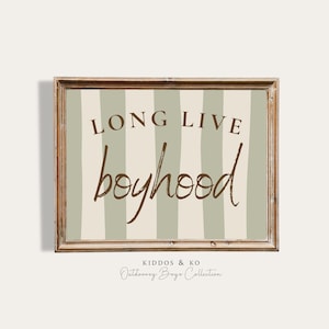 May include: A framed print with the words "LONG LIVE boyhood" in brown script. The background has vertical stripes of light green and cream. The frame is a distressed wood. The bottom of the print reads "KIDDOS & KO Outdoorzy Boys Collection."