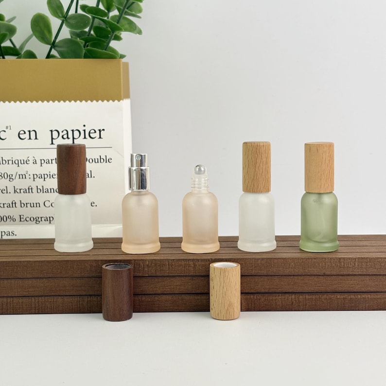 Assorted pastel frosted glass bottles (wood/bamboo caps) – open cap detail, eco-friendly option for DIY beauty formulations