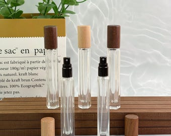 Botellas de vidrio transparente con atomizador y tapas de madera: envases recargables de viaje para aromaterapia, aceites esenciales y fragancias caseras.