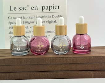 Frascos goteros de vidrio coloreado con tapas de bambú: envases con estampado floral para aceites esenciales, mezclas de perfumes y productos de cuidado de la piel en formato de viaje.