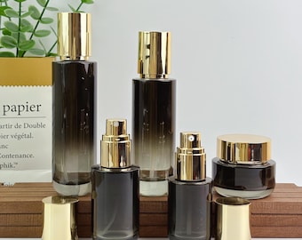 Envase de vidrio con degradado oscuro para el cuidado de la piel, elegante botella de loción con dosificador dorado, botella con pulverizador, tarro para crema para productos de belleza de marcas exclusivas.