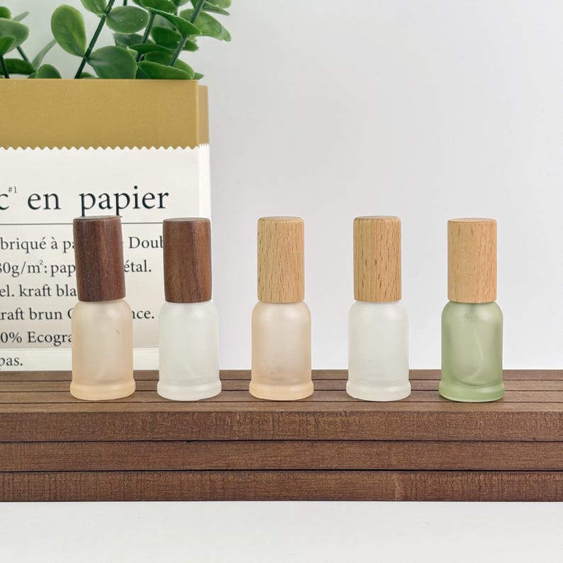 Pastel frosted glass bottles (peach/white/green) with wood caps – ideal for essential oils, serums, or small beauty brand packaging