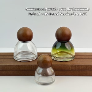 May include: Three glass bottles with wooden stoppers. One bottle is clear, another has a green and yellow gradient, and the third is also clear. The bottles are arranged on a brown wooden surface.
