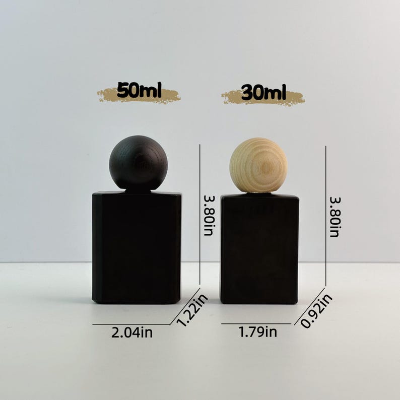May include: Two black rectangular perfume bottles with wooden spherical tops. The bottles are 3.80 inches tall. One bottle has a dark top, the other a light wood top. The bottles are labeled 50ml and 30ml.