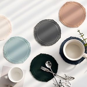 May include: Set of six decorative silicone coasters in various colors, including gray, blue, green, and pink. Each coaster features an intricate, ornate design around the edge.