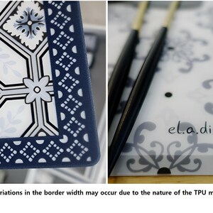 May include: A close-up of two rectangular placemats with a decorative design. One features a navy blue border with white geometric patterns and floral accents. The other has a transparent surface with a floral pattern and the text "el.a.dining".