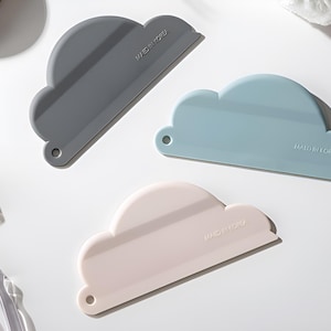 May include: Three cloud-shaped silicone spatulas in gray, light blue, and pink. Each spatula has the word "MAGNIFY" printed on it.