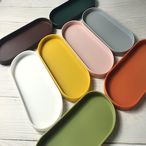 May include: Set of 8 oval-shaped silicone trays in various colors, including brown, white, yellow, pink, gray, orange, and green. The trays are made of flexible silicone and are perfect for serving snacks, dips, or other small items.