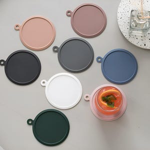 May include: Set of eight silicone coasters in various colors, including black, white, pink, blue, and green. The coasters are round and have a raised lip around the edge. They are perfect for protecting surfaces from heat and spills.