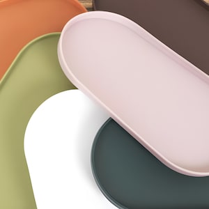 May include: Five oval-shaped silicone trays in different colors: orange, green, white, pink, and dark green. The trays are stacked on top of each other.