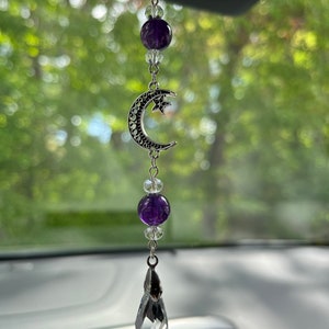 May include: A silver car charm with a crescent moon and star design, accented with purple amethyst beads and clear crystal beads. The charm hangs from a silver chain.