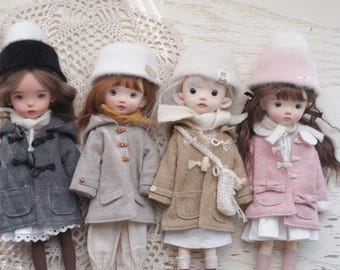 May include: Four dolls dressed in winter coats and hats. The dolls have different hair colors and wear coats in gray, beige, and pink. Each doll has a unique hat, including a black pom-pom hat and a white fuzzy hat.