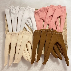 May include: A set of 10 pairs of doll leggings in white, pink, beige, and brown. The leggings are made of a ribbed fabric and have a stretchy fit.