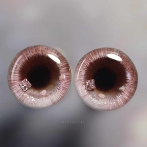 May include: Two brown and white doll eyes with pink glitter and a small pink square rhinestone in each eye.