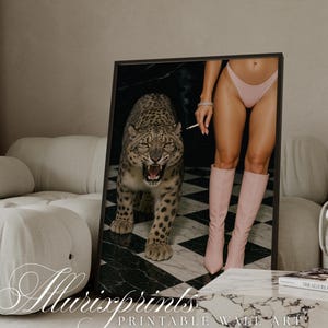 May include: A framed print showing a snarling leopard and a person in pink underwear and boots holding a cigarette. The print is set against a black and white checkered background. The print is displayed on a marble coffee table.