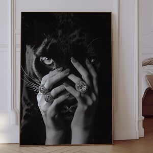 May include: Black and white photograph of a woman's hands covering her face. The woman is wearing large diamond rings. The background is a black panther.