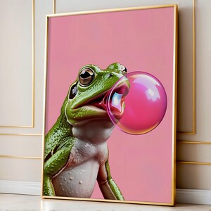 May include: A green frog with a pink bubble blowing out of its mouth. The frog is on a pink background.