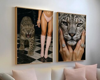 Könnte beinhalten: Zwei gerahmte Kunstdrucke. Einer zeigt einen knurrenden Leoparden mit einer Person, die eine brennende Zigarette hält. Der andere zeigt eine Nahaufnahme des Gesichts eines Schneeleoparden mit Händen, die Ringe tragen. Beide haben goldene Rahmen.