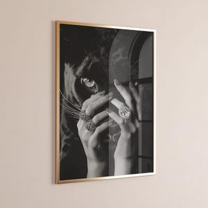 May include: Black and white photograph of a woman's hands holding a black panther's face. The woman is wearing several large diamond rings.