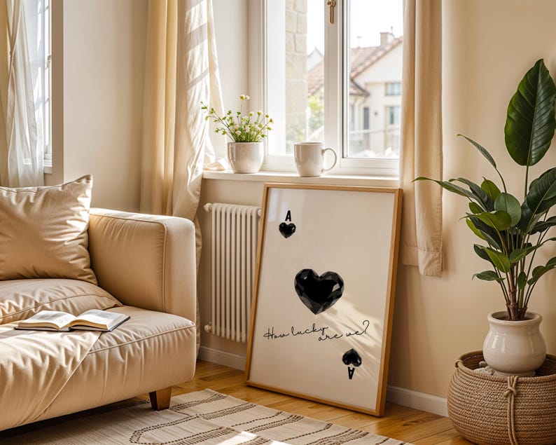 May include: A framed print with a black and white design of a playing card. The card is the Ace of Spades and features a large black heart in the center. The text "How lucky are we?" is written in cursive below the heart.