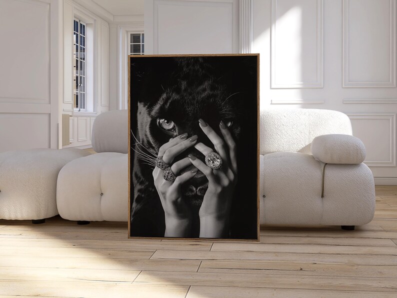 May include: Black and white photo of a woman's hands covering her face. The woman is wearing rings with large gemstones. The background is a black panther.