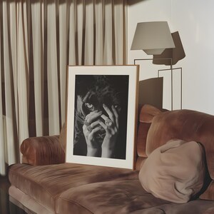 May include: A framed black and white photograph of a woman's hands covering her face, with a black panther's eye peeking out from behind her fingers. The woman is wearing several rings with large gemstones.