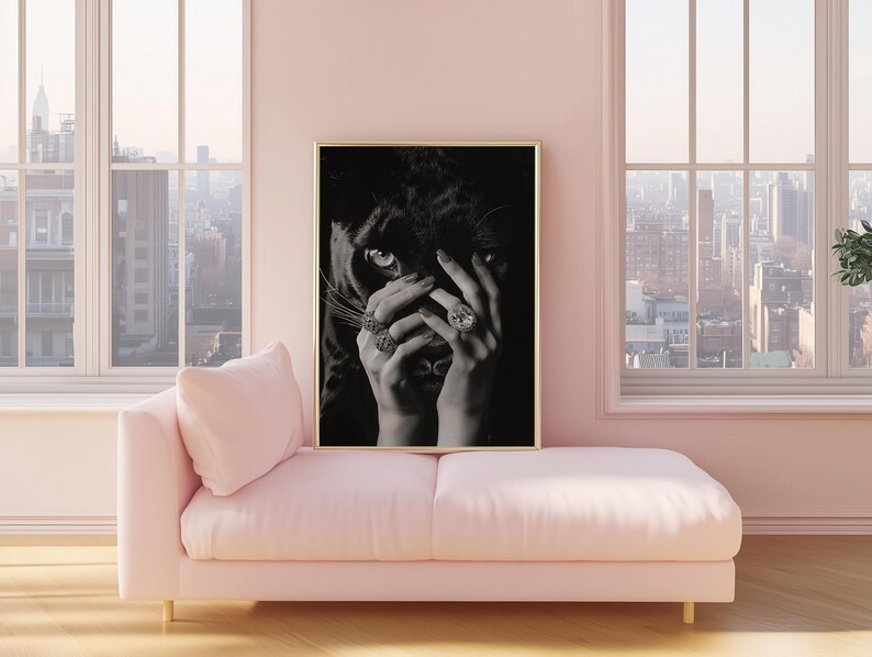 May include: Black and white photograph of a woman's hand covering her face, with a black panther's face peeking out from behind her fingers. The woman is wearing several rings with large gemstones.