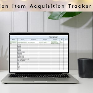 May include: A laptop showing a spreadsheet labelled "Auction Item Acquisition Tracker" on a white desk. A wooden pencil holder with pencils, a black mug, and a notebook are also on the desk. The background is a white wall.