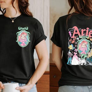 Pu&ograve; includere: Maglietta nera con una stampa grafica di Ariel de La Sirenetta. La parte anteriore della maglietta presenta un ritratto di Ariel in una cornice con un fiocco. La parte posteriore della maglietta presenta una grafica pi&ugrave; grande di Ariel con altri personaggi del film, tra cui Sebastian, Flounder e Ursula. Il testo "Ariel" e "La Sirenetta" &egrave; anche stampato sul retro della maglietta.