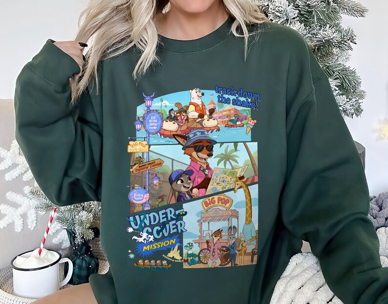 May include: Dark green sweatshirt featuring a colorful graphic from the movie Zootopia. The graphic includes the text "track down the shake!" and "Undercover Mission" with various cartoon characters and scenes. The sweatshirt is a crew neck style.