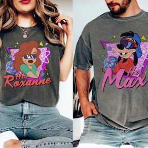 Könnte beinhalten: Zwei graue T-Shirts mit Cartoon-Charakteren. Eines zeigt Roxanne mit dem Text "His Roxanne", das andere Max mit dem Text "Her Max". Beide Shirts haben ein Retro-Design mit Neonfarben, das an die 90er Jahre erinnert.
