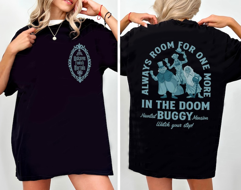 Może przedstawiać: Czarny t-shirt z białym kołnierzem. Prz&oacute;d ma turkusowy owalny wz&oacute;r z napisem "Welcome Foolish Mortals". Tył przedstawia turkusową grafikę z napisem "Always Room For One More In The Doom Haunted Buggy Mansion Watch your step!"