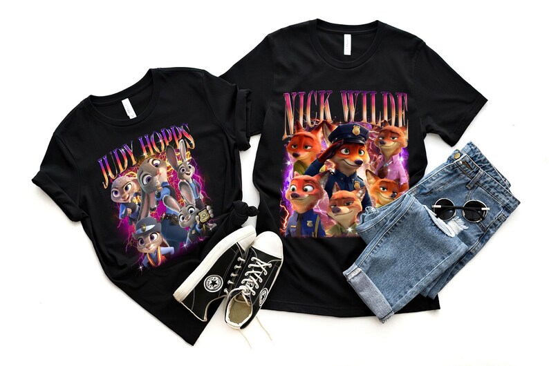 May include: Two black t-shirts featuring characters from the film Zootropolis. One shirt displays "Judy Hopps", the other "Nick Wilde". The image also includes black trainers, blue jeans, and sunglasses.