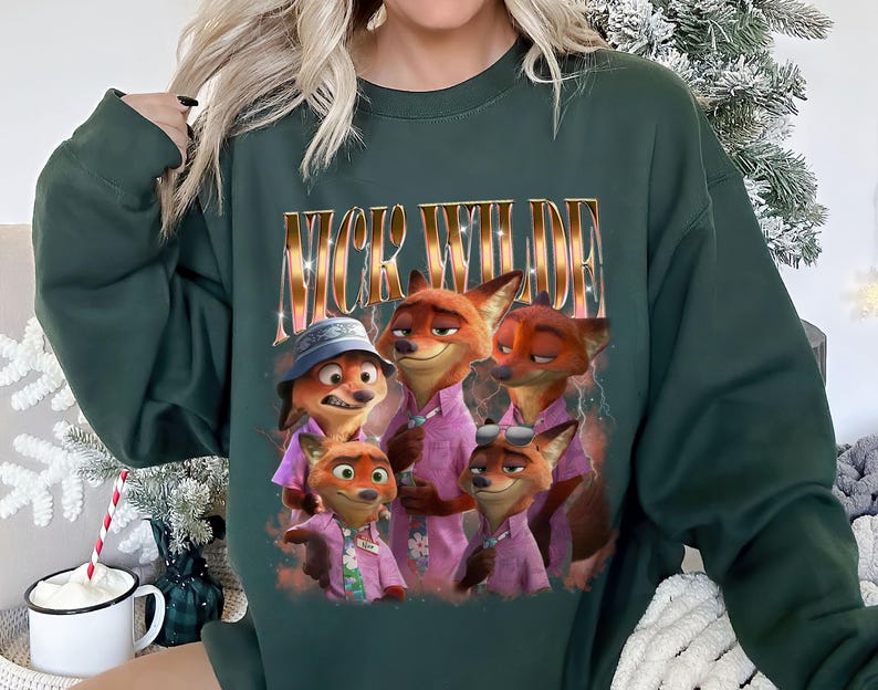 May include: Dark green sweatshirt featuring a graphic of Nick Wilde from Zootopia. The image shows Nick Wilde and other fox characters in pink shirts. The text "NICK WILDE" is printed above the characters in a gold, glittery font.