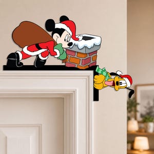 May include: A decorative corner sign featuring Mickey Mouse dressed as Santa Claus with a brown sack, leaning over a brick chimney with snow on top, and Pluto wearing a red Santa hat and a green scarf, peeking around the corner of a door frame.